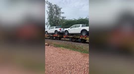 Dozens of pickup trucks seen being delivered on a train in Cambodia