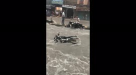 Stream of motorbikes swept down street by raging flood in Jodhpur, NW India