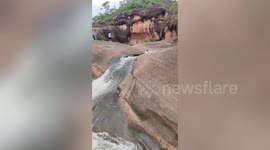 Tourists glide over rocks in 'natural water slide' during rainy season in northeast Thailand