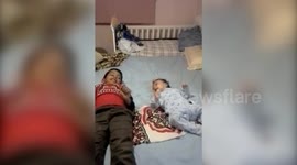 A Young Boy And Baby Kick On Bed