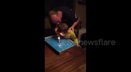 Confused toddler puts out lit birthday cake candle with his forehead