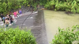 Locals go fishing in fast-flowing weir following heavy rain in Thailand