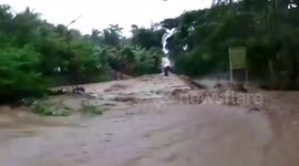 Swollen river surges onto road after storms leaving motorists stranded