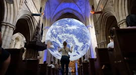 Visitors at West London church gaze upon a 7-metre model of the earth by artist Luke Jerram