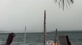 Waterspout forms next to docked boats on beach in the Philippines