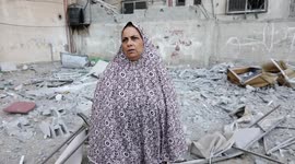 A Palestinian woman looks at rubble in vicinity of high-rise hit by Israeli strikes