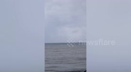 Waterspout passes by boats on beach in the Philippines