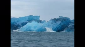 Iceberg rolling over directly in front of boat in Jökulsárlón, Iceland