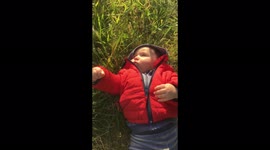 Baby exploring the world touching grass laying on ground in the wind