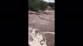 Flash flood in Tucson Arizona from monsoon storm rain washes out and destroys the road. Family living near by spectates and can be heard worrying about the damage.