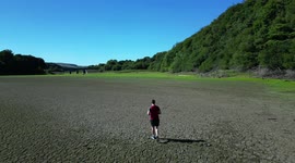 Drone view of man exercising on dry and cracked empty reservoir basin at Lindley Wood Reservoir, North Yorkshire, UK.