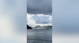 Spectacular waterspout tornado shimmers in sun between islands in the Philippines