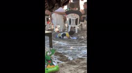 Kid sleeping on beach given rude awakening as waves washes over him
