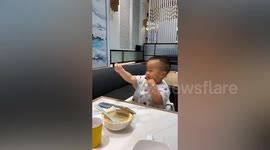 Toddler practises boxing by copying movements he sees on mobile phone