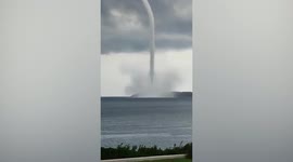 Incredible S-shaped waterspout tornado twists next to coastal village in Greece