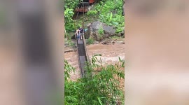 Brave couple cross rope bridge as river rages just inches below them in Thailand