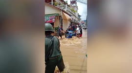 Locals push carts and motorcycles across raging floodwater in Myanmar