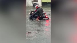 Motorcycle riders get stuck on flooded road after heavy rain in the Philippines