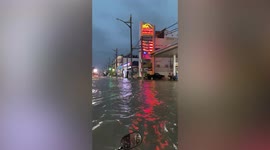 Cars splash through flooded road after monsoon rain storm in Cambodia