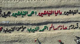 An aerial view shows people gathered along the coast of Gaza City, around names carved in the sand of the children who were killed during the latest round of conflict between Israel and Palestinian militants, during a commemorative event