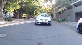 Man throws object at cyclist. Cyclist has item thrown at them from a car