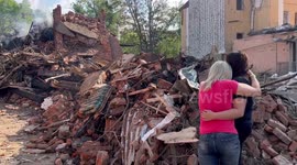 Women hug as officials carry out search and rescue operation on bombed Kharkiv neighbourhood