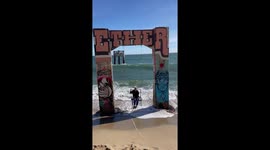 Girl attempting to take cute picture at California beach is drenched by wave