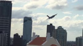 Huge cargo plane flies between skyscrapers through middle of city