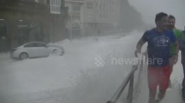 Massive waves smash into the rocks at the coast and soak a group of tourists