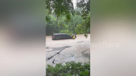 Car stuck on flooded road as heavy rain hits northern Thailand