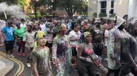 Early rising Notting Hill Carnival revellers spray each other in paints and powders at opening event