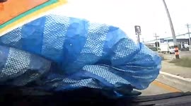 Loose tarpaulin blows from pickup truck onto car travelling behind