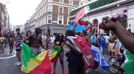 Notting Hill Carnival 2022 - revellers wrapped in Caribbean flags on the way to carnival