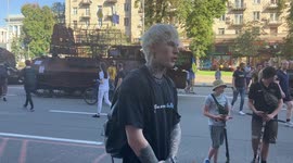 A young hip Ukrainian man tells about his experience of the war start on Independence Day, in Kyiv, broken Russian equipment behind him
