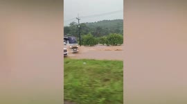Commuters struggle through flooded road in Thailand