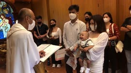 Giggly baby boy amuses priest during baptism ceremony