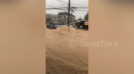 Pickup truck pushed back by muddy flood surging down street in Thailand