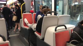 Selfish teenager puts feet up on seat as other passengers forced to stand on packed light rail in Sydney, Australia