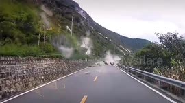Car reverses to avoid being hit by rocks rolling down mountain