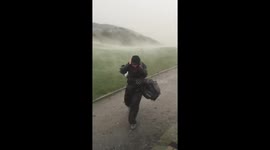 Golfer struggles against the wind as storm hits golf course