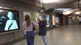 Londoners have their photos taken next to Queen Elizabeth II portait on the tube