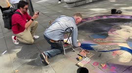 A chalk artist draws a tribute to the Queen on a pavement in London’s West End
