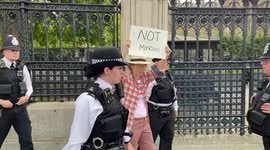 London police lead anti-monarchy protester holding “Not my king” sign outside Parliament