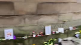 People bring flowers to pay tribute to the Queen at Holyrood Palace, Edinburgh, UK