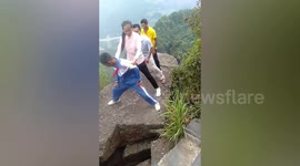 Terrifying moment family shake wobbly rock on cliff edge in China