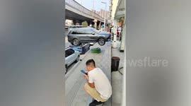 Woman drives car onto vehicle's roof after reversing out of raised car park