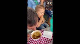 Toddler puts his fast, little hands to work while eating noodles with dad