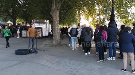 Busker sings to queue of people waiting to see the Queen lying in state