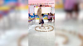 Kindergarteners hone motor skills by walking along wooden block 'labyrinth' at school