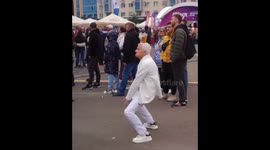Charismatic old man dances with glass of beer on head